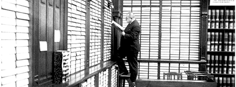 Alt-Text: Seinerzeit in der Bibliothek: Mann steht auf Leiter vor Regalreihen