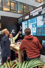 Three people chatting in front of a project poster