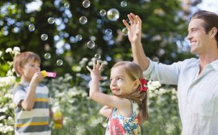Kinder und Vater spielen mit Seifenblasen
