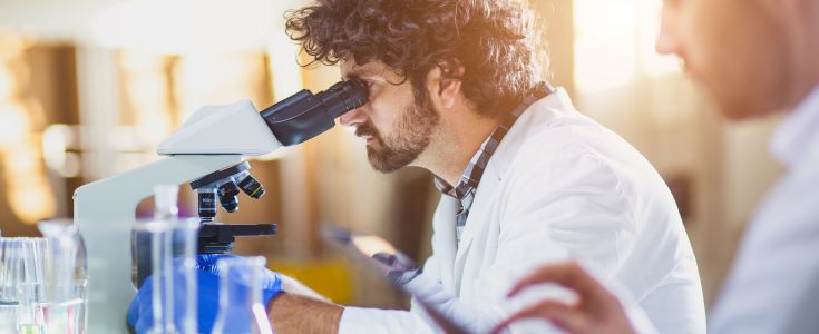 Forscher schaut in ein Mikroskop