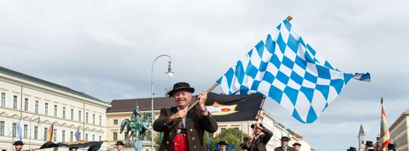Bayerische Fahne schwenkender Mann in Tracht