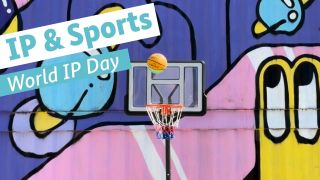 A basketball flies toward a basketball hoop in front of a wall covered in graffiti 